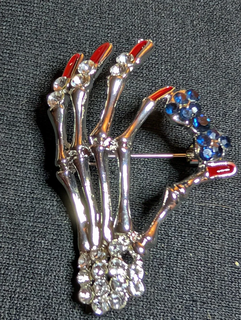 Silver Skeletal Hand Brooch with Red Nail and Blue Crystal Accents